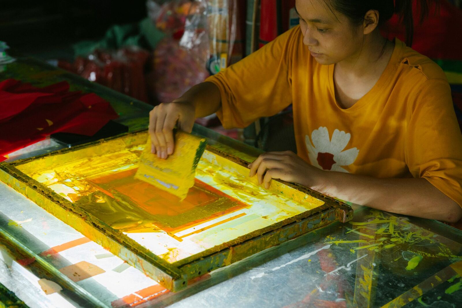 Focused young adult screen printing art indoors, showcasing creativity.