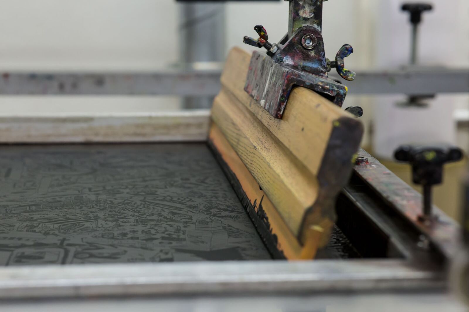 Detailed view of a screen printing setup with a wooden squeegee in Luzern, Switzerland.